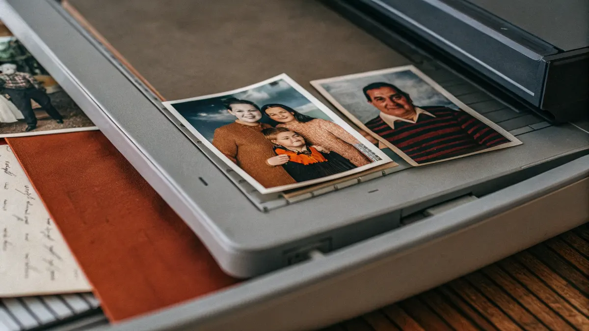 Flatbed scanner digitizing vintage family photographs and handwritten genealogy records