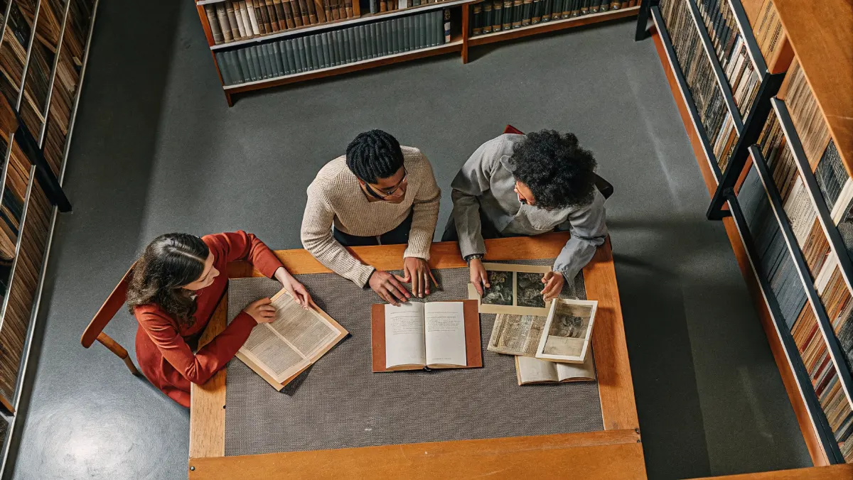 Group of researchers examining old documents and family trees at a library table